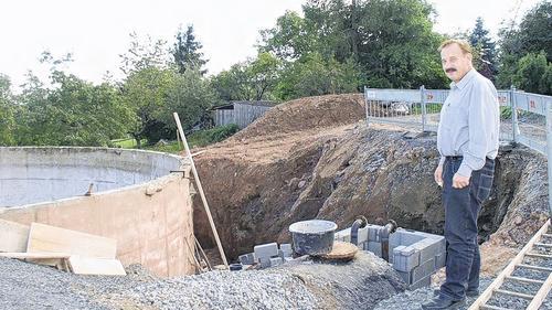 Engagement für die Nahwärmeversorgung: Franz Söder neben dem Warmwasser-Pufferspeicher. Links im Bild die ehemalige Güllegrube, die zu einem Hackschnitzel-Bunker umfunktioniert wird. Auf der Fläche dahinter wird das Heizhaus seinen Standort haben.