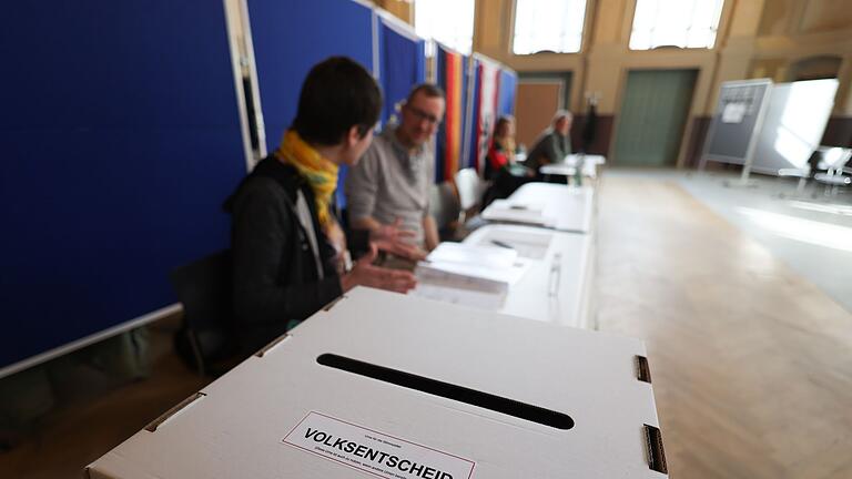 Volksentscheid für ehrgeizigere Klimaziele in Berlin.jpeg       -  Wahlhelfer sitzen vor einer Wahlurne in einem Wahllokal im Bildungs- und Kulturzentrum Peter Edel in Berlin-Weissensee.