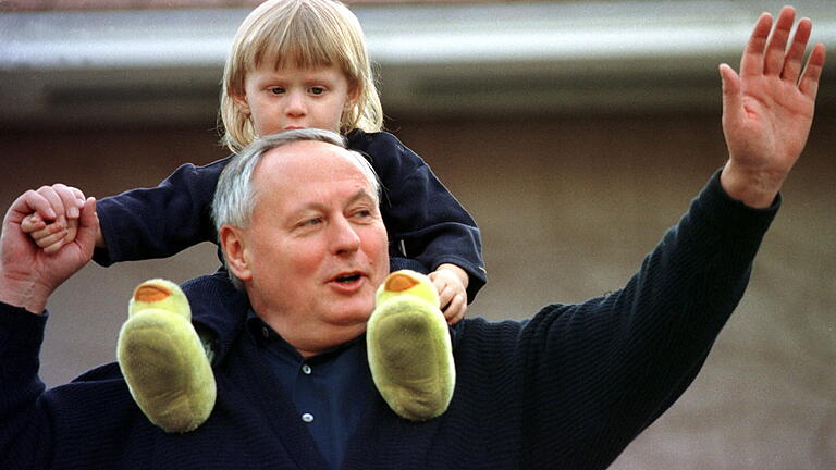 Lafontaine zeigt sich mit Sohn Carl-Maurice.jpeg       -  Keine zwei Tage nach seinem Rücktritt winkt Oskar Lafontaine von der Terrasse seines Hauses in Saarbrücken einem Nachbarn zu. Auf dem Rücken hat er seinen zweijährigen Sohn Carl-Maurice.