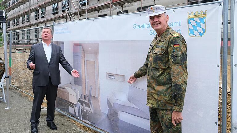 So soll es werden: Bauminister Christian Bernreiter und  Brigadegeneral Michael Matz zeigten am Rande des Richtfestes auf einen Bauzaun. Dort ist eine der künftigen Unterkünfte im Hotelstandard abgebildet.&nbsp;