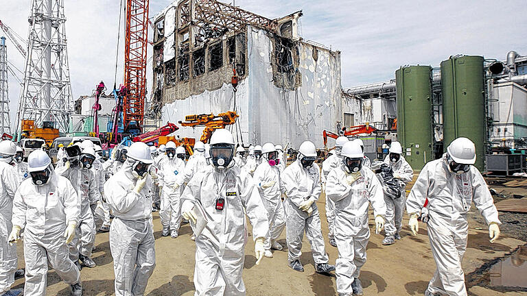 Vermeidbarer GAU: Eine Untersuchungskommission geht davon aus, dass gravierende Sicherheitsmängel zur Katastrophe von Fukushima geführt haben. Das Bild zeigt Mitarbeiter des Betreibers Tepco vor dem kollabierten Block 4 im AKW Fukushima.