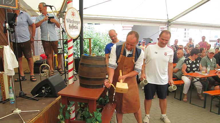 Bürgermeister Johannes Krumm (Mitte) gelang sein erster Bieranstich beim zweiten Schlag. Gemeinderat Tobias Warter (rechts) wartet bereits mit den Freibier-Krügen.       -  Bürgermeister Johannes Krumm (Mitte) gelang sein erster Bieranstich beim zweiten Schlag. Gemeinderat Tobias Warter (rechts) wartet bereits mit den Freibier-Krügen.