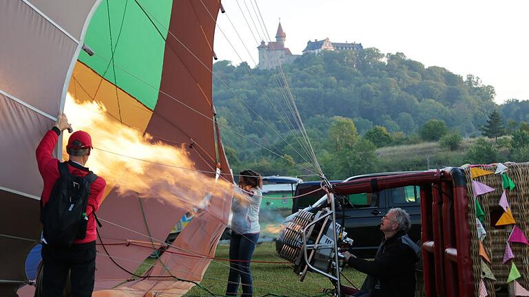 Fertig zum Aufstieg: Vor der geschichtsträchtigen Kulisse der Veste Heldburg bläst Georg Leupold (rechts) heiße Luft in die Ballonhülle.