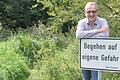 Bürgermeister Andreas Hoßmann mit dem neuen Schild 'Begehen auf eigene Gefahr'. Dahinter beginnt der 'Dschungelpfad'.