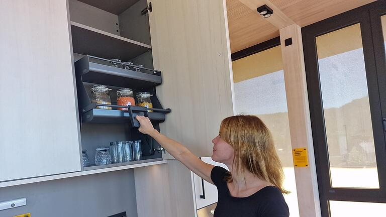 Stefanie Tratt demonstriert, wie ein absenkbarer Oberschrank auch hohe Bereiche in der  Küche erreichbar  macht.       -  Stefanie Tratt demonstriert, wie ein absenkbarer Oberschrank auch hohe Bereiche in der  Küche erreichbar  macht.