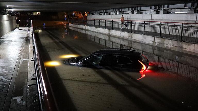 Sommergewitter in Baden-Württemberg       -  Nach einem schweren Gewitter steht ein Auto in Bruchsal bis zur Motorhaube im Wasser.