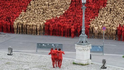 Installationsprojekt 'Der Ring' mit 1000 nackten Menschen       -  Unter den Blicken hunderter Freiwilliger tagen am Samstag (23.06.2012) in München vor der Bayerischen Staatsoper beim Installationsprojekt &quot;Der Ring&quot; zwei Mitwirkende einen Dritten, der nicht mehr Auftreten kann. Zum Auftakt der Opernfestspielen München posieren bei der Installation des US-Künstlers Spencer Tunick mehr als 1000 nackte Menschen vor dem Nationaltheater und an anderen Orten in der Stadt.