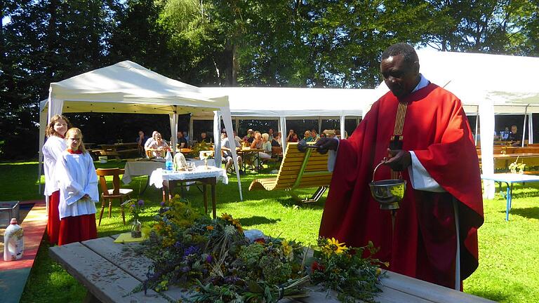 Pfarrer Francois Tiando segnet die Kräuterbüschel beim Pfarrfest in Osthausen.