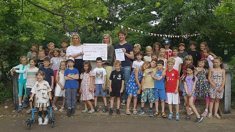 Anja Frühwirth (Schulleitung Unesco-Grundschule Würzburg-Heuchelhof), Maria Hisch (Bildungsreferentin DAHW), Christof Balling (Musikpädagoge und Initiator des „Kinderwelten“-Films) und die Kinder der Ganztagsklassen 1A und 1B.