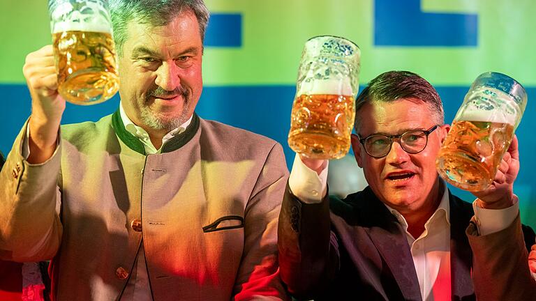 Politischer Frühschoppen auf dem Volksfest Gillamoos       -  Markus Söder (l, CSU), Ministerpräsident von Bayern, und Boris Rhein (r, CDU), Ministerpräsident von Hessen, stoßen beim Politischen Frühschoppen Gillamoos gemeinsam auf der Bühne mit einer Maß Bier an.