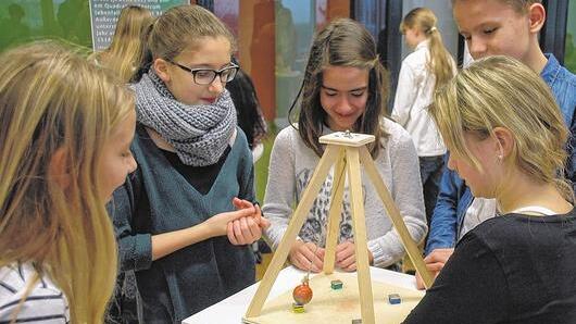 Schüler der 6. Klasse experimentieren mit einem Magnetpendel. Dabei wird klar: Schon die kleinste Veränderung der Stelle, an der das Pendel losgelassen wird, kann dazu führen, dass die Eisenkugel am Pendel von einem anderen Magneten eingefangen wird.