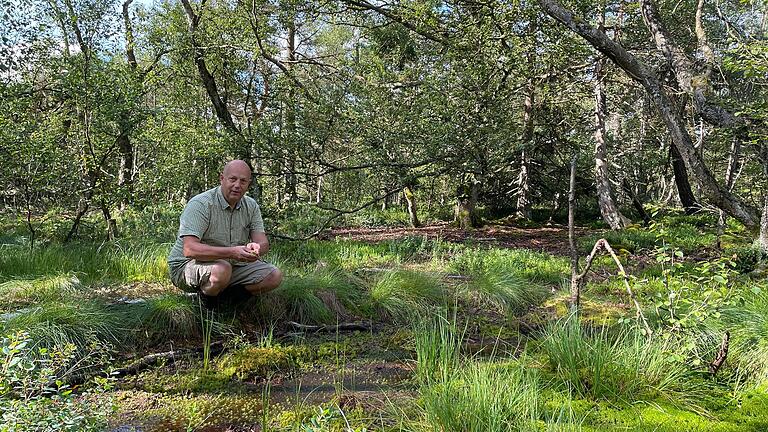 Michael Dohrmann vom Verein Naturpark und Biosphärenreservat Bayerische Rhön zeigt die Auswirkungen eines intakten Stauwehrs auf die Natur im Moor.