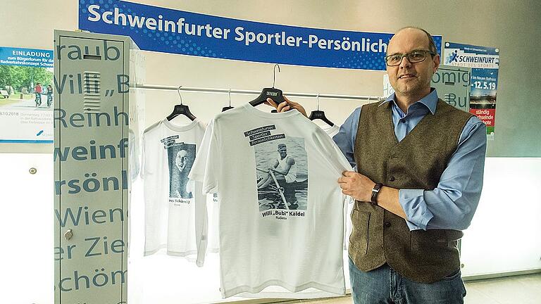 Schweinfurter Sportler-Persönlichkeiten auf T-Shirts: Christian Kühnel präsentiert eines der Shirts, die im Rahmen der Ausstellung ebenfalls zu sehen sind. Hier hält er das Hemd mit dem Konterfei von Willi &bdquo;Bubi&ldquo; Kaidel&ldquo; hoch, der 1936 bei den Olympischen Spielen in Berlin gemeinsam mit Joachim Pirsch im Doppelzweier die Silbermedaille holte. Kaidel startete für den Schweinfurter Ruder-Club Franken.