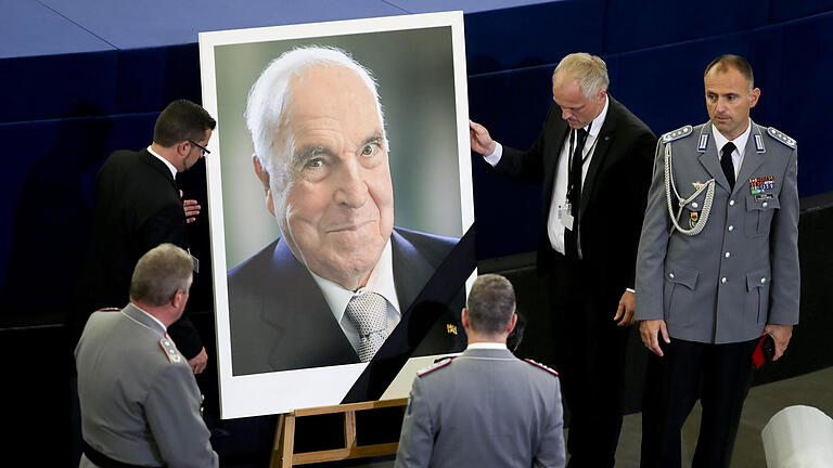 Trauerfeierlichkeiten für Altkanzler Kohl       -  Saaldiener stellen am 01.07.2017 vor dem europäischen Trauerakt für den verstorbenen Altkanzler Helmut Kohl im EU-Parlament in Straßburg (Frankreich) ein Porträt auf. Kohl war am 16.06.2017 im Alter von 87 Jahren gestorben. Der Kanzler der Deutschen Einheit war 16 Jahre im Amt. Foto: Michael Kappeler/dpa +++(c) dpa - Bildfunk+++
