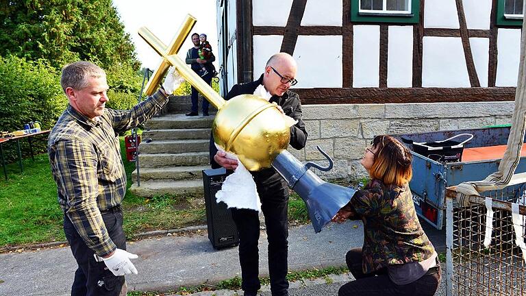 Pfarrerin Christel Kupfer steckt den Zylinder mit den alten und neuen Chronikdokumenten in den Turmknopf, der nun wieder die Dorfkirche von Weimarschmieden krönt. Ein Arbeiter der Firma Dietz aus Fladungen sowie der Leiter des Gesamtsanierungsprojekts, Christoph Bauer (Mitte), halten die nicht ganz leichte Turmbekrönung. Pfarrerin Christel Kupfer steckt den Zylinder mit den alten und neuen Chronikdokumenten in den Turmknopf, der nun wieder die Dorfkirche von Weimarschmieden krönt. Ein Arbeiter der Firma Dietz aus Fladungen sowie der Leiter des Gesamtsanierungsprojekts, Christoph Bauer (Mitte), halten die nicht ganz leichte Turmbekrönung.