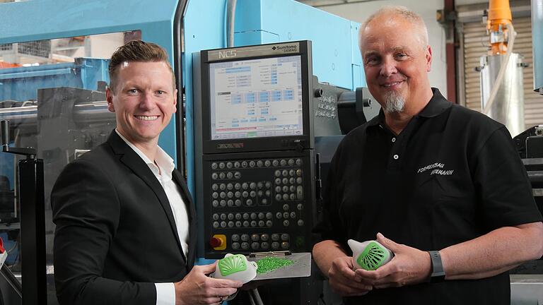Die Tüftler Simon Gerlach (links) und Thomas Niemann entwickelten in kürzester Zeit eine wiederverwendbare Mund-Nasen-Maske. Stolz präsentieren sie das Produkt vor dem imposanten Fertigungsautomaten.
