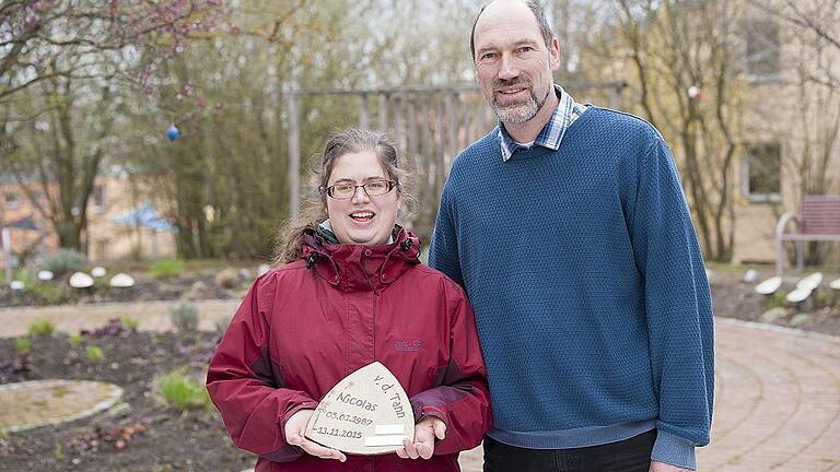 Auf dem Gelände des Blindeninstituts entsteht ein Gedenkort für Verstorbene, die hier gelebt haben: Annika von der Tann hält die Namenstafel für ihren Bruder Nicolas in der Hand, die auf einer etwa zehn Zentimeter hohen Stele in den Blumenbeeten angebracht wird. Georg Ruhsert ist Seelsorger im Blindeninstitut und hat bei Schülern, Mitarbeitern und allen Bewohnern Ideen für den gerade entstehenden Gedenkort gesammelt und deren Umsetzung organisiert. Auf dem Gelände des Blindeninstituts entsteht ein Gedenkort für Verstorbene, die hier gelebt haben: Annika von der Tann hält die Namenstafel für ihren Bruder Nicolas in der Hand, die auf einer etwa zehn Zentimeter hohen Stele in den Blumenbeeten angebracht wird. Georg Ruhsert ist Seelsorger im Blindeninstitut und hat bei Schülern, Mitarbeitern und allen Bewohnern Ideen für den gerade entstehenden Gedenkort gesammelt und deren Umsetzung organisiert.