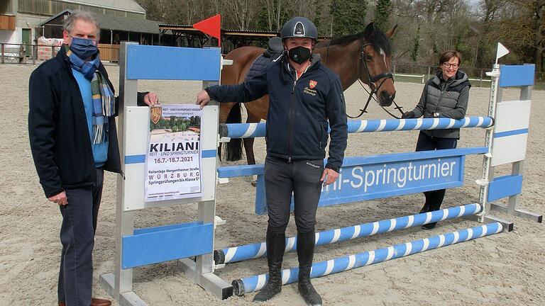 Vorsitzender Jochen Klingler (links) präsentiert mit Reitlehrer Lars Niebuhr das neue Plakat für das Kiliani-Reit- und Springturnier, rechts Geschäftsführerin  Andrea Kranig mit dem Pferd 'Leikas Lausejunge'.