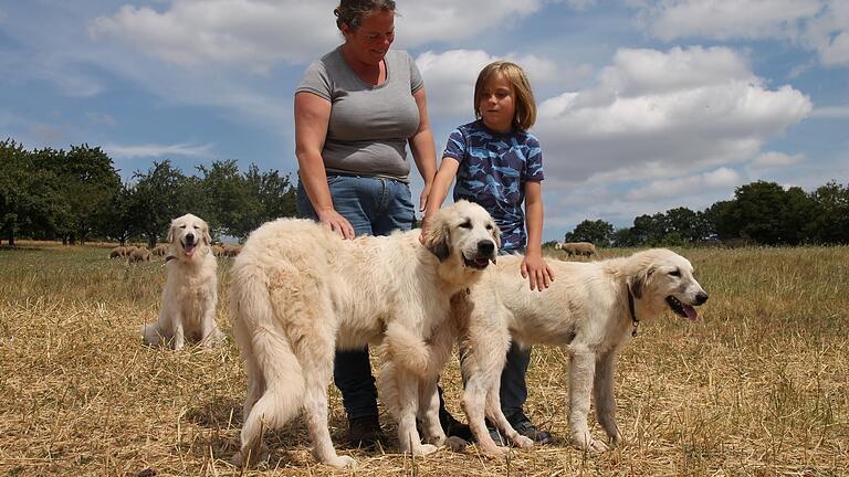 Christiane Geiger mit Sohn Emil und den jungen Herdenschutzhunden Patou (links) und Paulette. Im Hintergrund wacht Uschi.