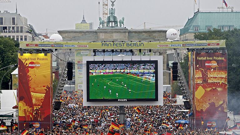 Public Viewing bei der Fußball-WM 2006 in Berlin.jpeg       -  Soll auch dieses Jahr möglich werden: Tausende Zuschauer verfolgen auf der Fanmeile am Brandenburger Tor in Berlin ein WM-Fußballspiel von Deutschland.