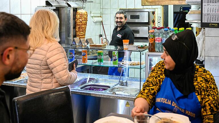 Immer wieder während des Abendessens kommen Kundinnen und Kunden in den Dönerladen in Würzburg. Für sie unterbricht Ramazan Acar das Essen gern. Immer wieder während des Abendessens kommen Kundinnen und Kunden in den Dönerladen in Würzburg. Für sie unterbricht Ramazan Acar das Essen gern.