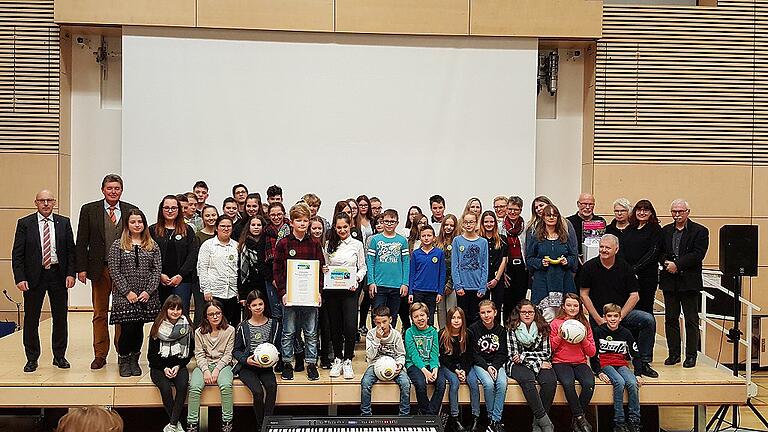 Stolz präsentieren die Schulsprecher Aylin Kaya und Paul Würfel Mitschülern, Lehrern, Vertretern der Fairtrade-Bewegung und offiziellen Gratulanten Urkunde und Wandtafel, die die Staatliche Realschule Gemünden als Fairtrade-School auszeichnen.