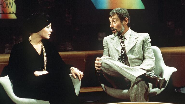 Romy Schneider und Dietmar Schönherr 1974       -  Moderator Dietmar Schönherr bemüht sich redlich in der Talkshow &bdquo;Je später der Abend&rdquo;, Romy Schneider zum Reden zu bringen. (Archivbild)