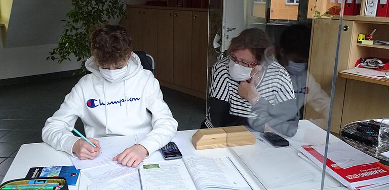Eine Plexiglasscheibe trennt den Nachhilfeschüler und die Nachhilfelehrerin während der Unterichtsstunde. Eine Plexiglasscheibe trennt den Nachhilfeschüler und die Nachhilfelehrerin während der Unterichtsstunde.