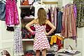Girl (9-11) looking in wardrobe, hands on hips, rear view       -  Entscheidende Frage im Mädchenzimmer: Wie style ich mich, was passt optimal zusammen?
