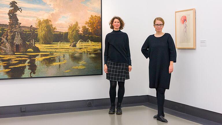 Kuratorin Henrike Holsing und Museumsleiterin Luisa Heese neben einem Werk aus dem Jahr 1878: 'See mit Pegasusgruppe im Hofgarten von Veitshöchheim (Verödet)'. Kuratorin Henrike Holsing und Museumsleiterin Luisa Heese neben einem Werk aus dem Jahr 1878: 'See mit Pegasusgruppe im Hofgarten von Veitshöchheim (Verödet)'.