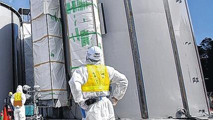 Fukushima: Ein Arbeiter im Schutzanzug schaut den Schweißarbeiten an einem Behälter für radioaktives Wasser zu.