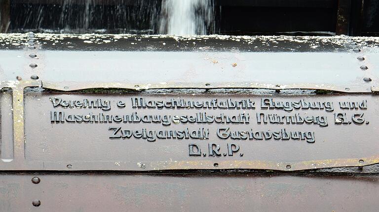 Die Aufschrift auf der Walze am Grundablass informiert über den Hersteller: Vereinigte Maschinenfabrik Augsburg und Maschinenbaugesellschaft Nürnberg A.G., Zweiganstalt Gustavsburg.