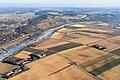 Der Main zieht seine eisige Bahn durch die schneefreie Winterlandschaft       -  (jos)   Beim Gleitschirmfliegen entstanden ist dieses Luftbild, das den zugefrorenen Main bei Karlburg noch mit schmaler Fahrrinne zeigt. Wo sich in den Feldern die Feuchtigkeit in Senken und Gräben hält, erscheinen dunkle Flächen und Streifen &ndash; Luftbildarchäologen können daraus ablesen, ob es Launen der Natur oder geschichtliche Spuren sind.