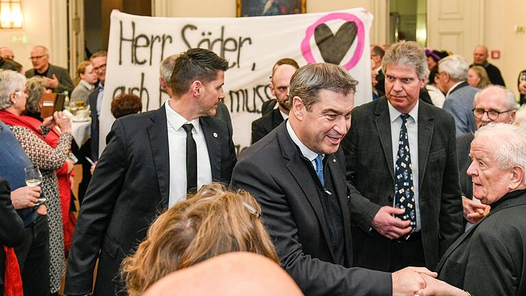 Während Ministerpräsident Markus Söder in der Würzburger Residenz Hände schüttelt, rollt Landwirt Eberhard Räder sein Leinentuch aus (hinten).