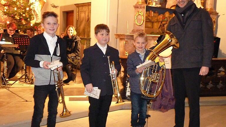 Ihre ersten großen Auftritt beim Weihnachtskonzert der Musikkapelle Spiesheim hatten Elia Klemenz, Simeon Kerler und Maximilian Ortner (von links). Mit einem Präsent bedankte sich Roland Marpoder vom Vorstandsteam bei den Jungbläsern.