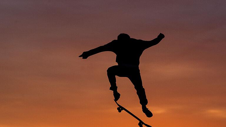 Ein Skater im Sonnenuntergang       -  Wer sicher auf dem Skateboard rollen kann, kann sich an ersten Tricks probieren.