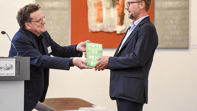 Geschenk mit Symbolcharakter: Andi Schmitt (VKU) überreicht Achim Könneke ein Bild, auf dem in umgekehrter Buchstabenfolge das Wort 'Optimismus' steht. Foto: Thomas&nbsp; Obermeier