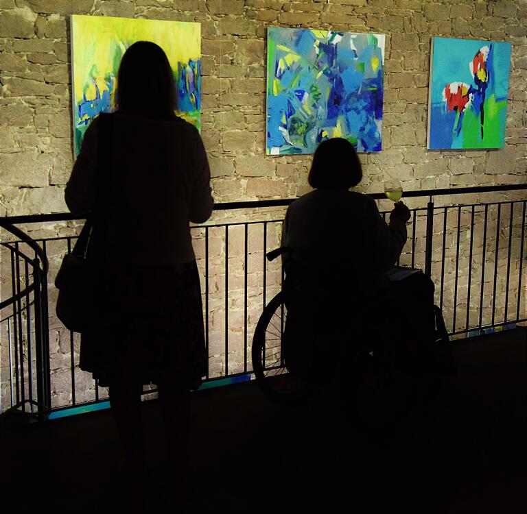 Zwei Besucherinnen der Ausstellung 'Eigenartig' im Franck-Haus vor Bildern der Wertheimer Malerin Ursula Donath.