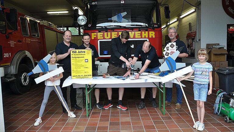 Die letzten Vorbereitungen laufen auf Hochtouren. Während Julia und Natalia Steinmetz die Täfele für den Festzug probetragen, kümmern sich Andreas Hümmer (stellvertretender Vorsitzender) und Dominik Döller um die Plakate, und Justus Wagenhäuser schraubt zusammen mit Kommandant Daniel Steinmetz die Schilder auf die Stöcke. Rechts daneben Vorsitzender Thomas Walter.