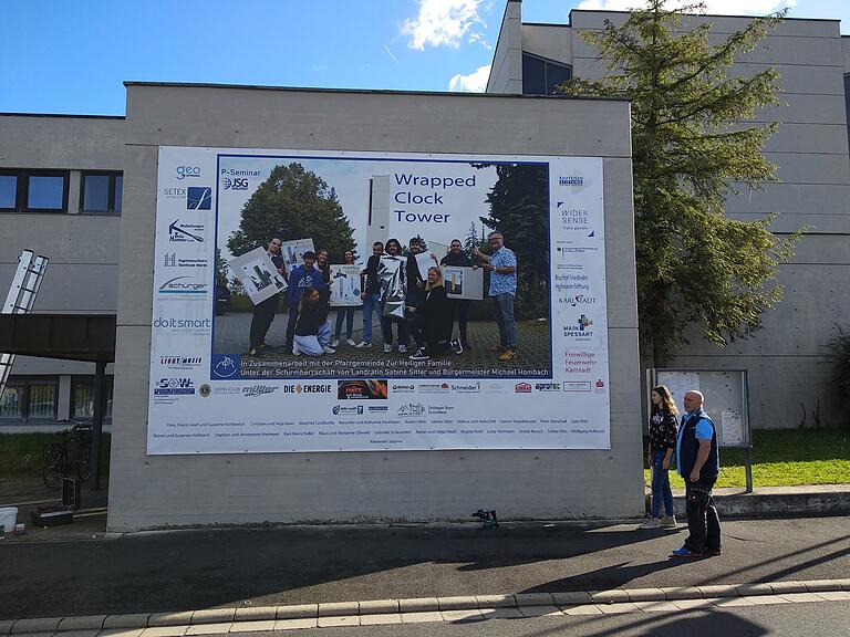 Ein Banner macht auf den „Wrapped Clock Tower“ aufmerksam. Gestaltet von den Schülerinnen und Schülern des Seminars. Es ist ein Dank an Unterstützer und Sponsoren.