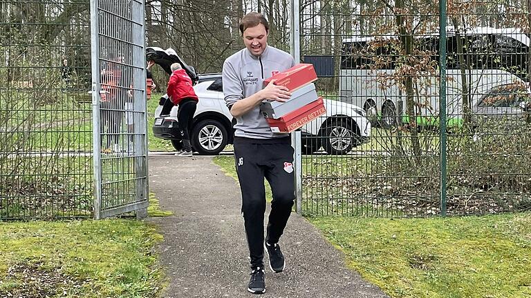 Julian Grell, der Trainer des TSV Aubstadt, trägt vor dem Auswärtsspiel beim FC Memmingen drei Kartons mit gekauften Fußballschuhen in die Kabine des Fußball-Regionalligisten.