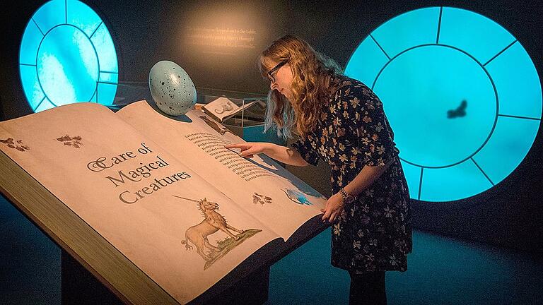 «Harry Potter: A History of Magic»-Schau in London       -  CEine Besucherin der Londoner Ausstellung mit dem Buch &bdquo;Care of Magical Creatures&ldquo;(&bdquo;Pflege magischer Geschöpfe). Es ist eines der Wahlfächer, das in der Harry-Potter-Schule Hogwarts von der dritten Klasse an zusätzlich zu den Hauptfächern belegt werden kann.