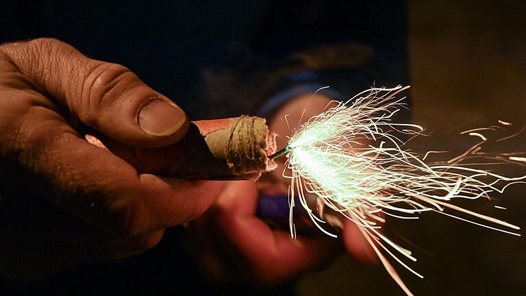 Silvester-Feuerwerk       -  Ein Mann zündet einen Böller am Silvesterabend an.