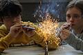 Orange-rot und weiß fliegen die Funken bei einem Experiment am Armin-Knab-Gymnasium, Kitzingen: Gregor und Lea pusten Eisenpulver und Magnesium in die Flamme des Bunsenbrenners.
