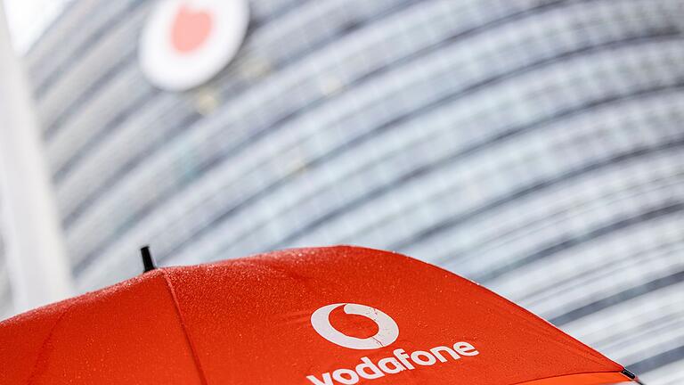 Vodafone-Deutschlandzentrale       -  Ein Passant geht mit einem aufgespanntem Regenschirm mit dem Logo von Vodafone an der Zentrale der Deutschlandtochter des britischen Vodafone-Konzerns vorbei.