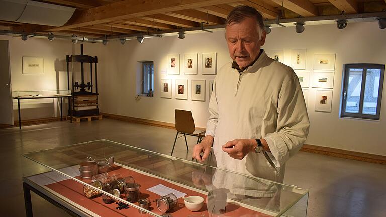 Hans- Ulrich Plener vor einer Vitrine, die Naturstoffe zur Farbherstellung zeigt.