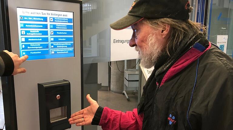 Ein älterer Mitbürger lässt sich die Auswahl an Menüpunkten am Ticketautomat im Servicecenter im Rathaus erklären.