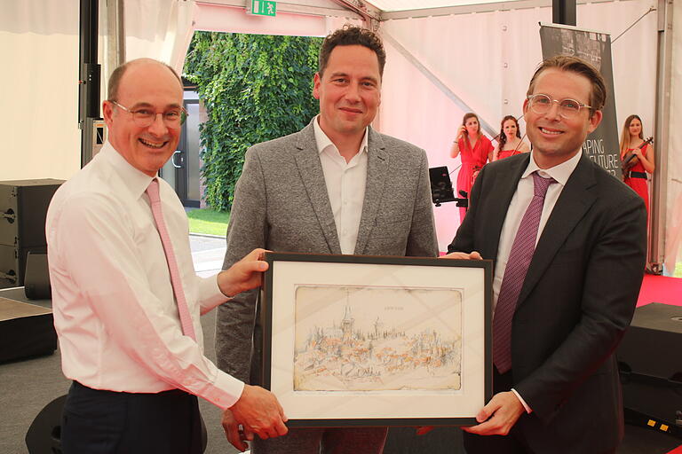 Das Bild zeigt (von links) Alexander Sorg, Bürgermeister Mario Paul und Michael Sorg bei der Überreichung einer Zeichnung der Lohrer Stadtansicht von Roland Schaller.