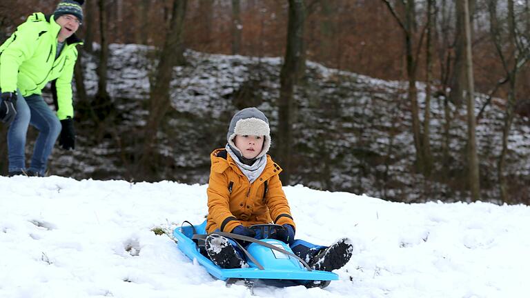 Zunächst die kleine Anschubhilfe vom Vater - und schon kann der vierjährige Louis aus Gleisenau, Ebelsbach, die rasante Abfahrt über die schneebedeckte Wiese starten.