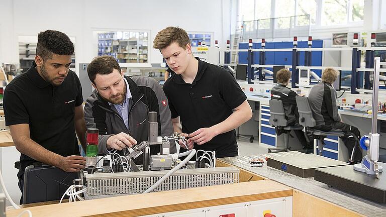 Ausbilder Michael Fromm unterstützt die Auszubildenden David Singh Vigo (l.) und Marco Landeck bei der Montage einer Steuerung. Die Lehrwerkstatt von SSI Schäfer ist einer der Schauplätze beim Tag der Ausbildung.